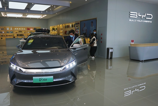 2021年，中国新能源汽车销量在全球市场的份额超过欧洲，成为全球最大的新能源汽车市场。比亚迪乘用车3月销量超10万辆，全系销售104338辆。图为消费者在杭州的一家比亚迪店内选购新能源汽车。视觉中国供图